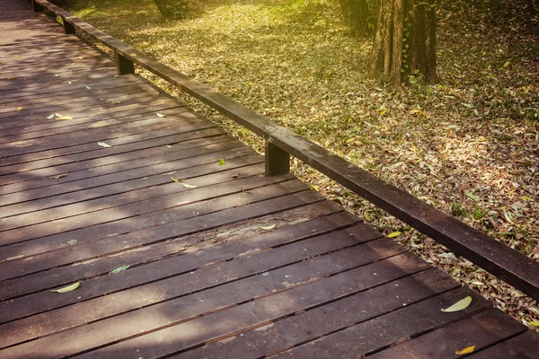 Vieille passerelle en bois avec des feuilles tombantes le matin de l'automne — Photo