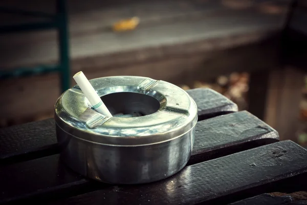 Colilla de cigarrillo en cenicero, cenicero de acero inoxidable sobre mesa de madera — Foto de Stock