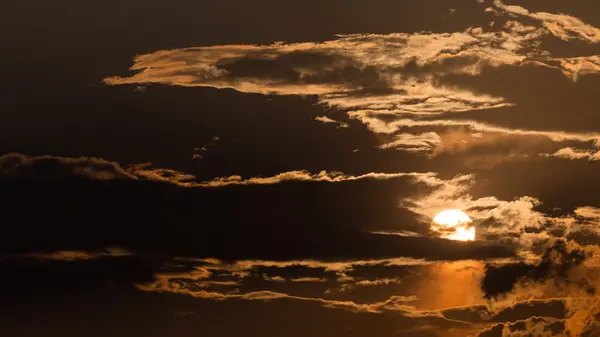 Оранжевое небо с солнцем и черными облаками — стоковое фото