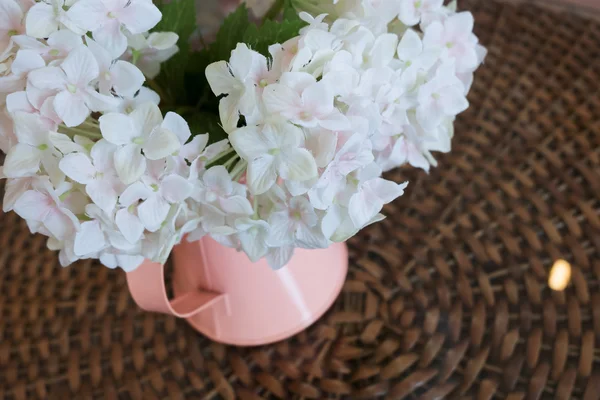 White plastic flowers in pink flower vase on the rattan weave — Stock Photo, Image