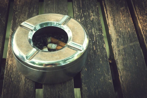 Bunda de cigarro em cinzeiro, cinzeiro inoxidável na mesa de madeira — Fotografia de Stock