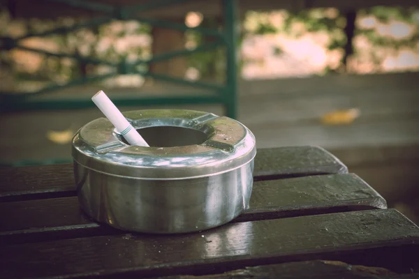 Colilla de cigarrillo en cenicero, cenicero de acero inoxidable sobre mesa de madera — Foto de Stock