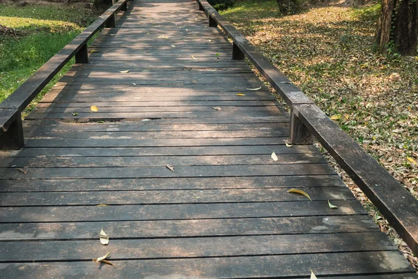 Antigua pasarela de madera con hojas que caen en la mañana del otoño — Foto de Stock