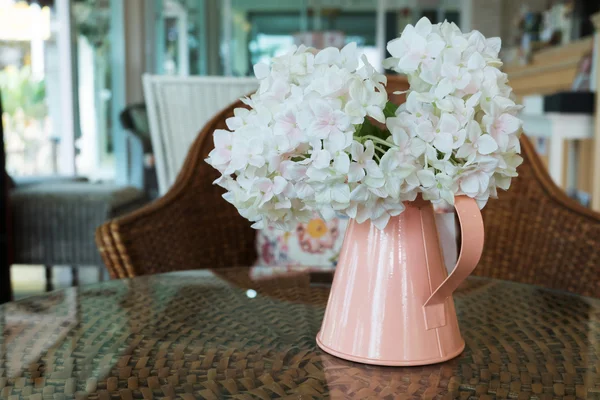 Flores de plástico branco em vaso de flores rosa no tecido de vime — Fotografia de Stock