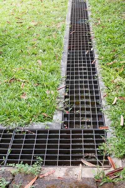 Iron grate of water drain in grass garden field — Stock Photo, Image