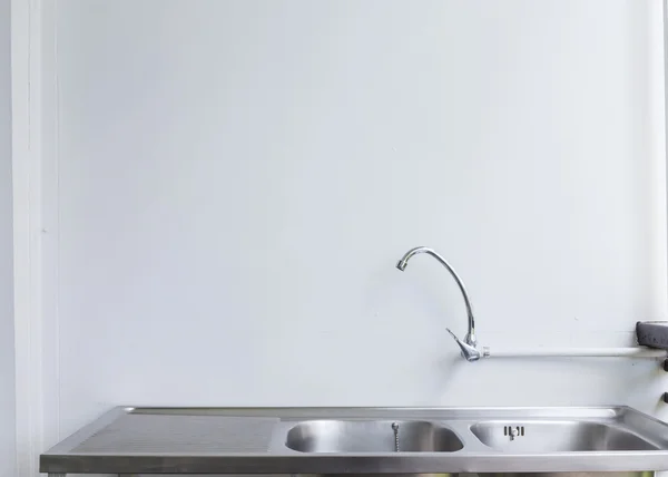 Pia de aço inoxidável e torneira na sala de cozinha branca — Fotografia de Stock