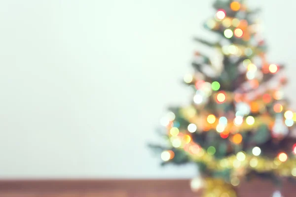 Lichtverschwommene Feier am Weihnachtsbaum mit weißer Wand — Stockfoto