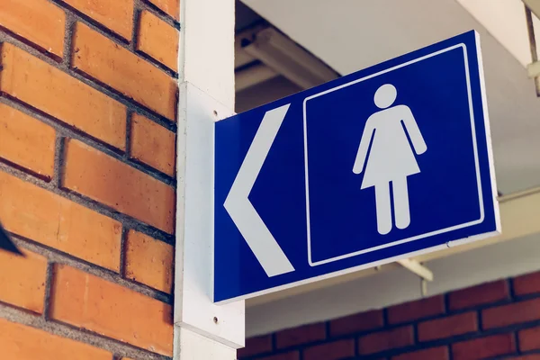 Sinais de banheiro com símbolo feminino e sinais de direção de seta — Fotografia de Stock