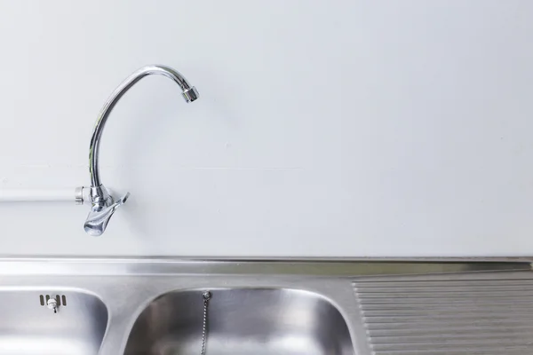 Évier et robinet en acier inoxydable dans la salle de cuisine blanche — Photo