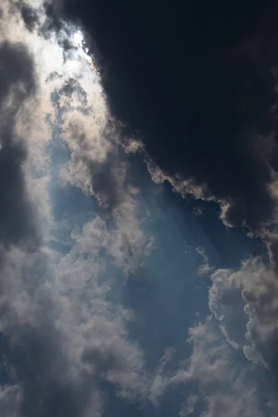 青い空を背景に日光の雲の切れ間から太陽光線 — ストック写真