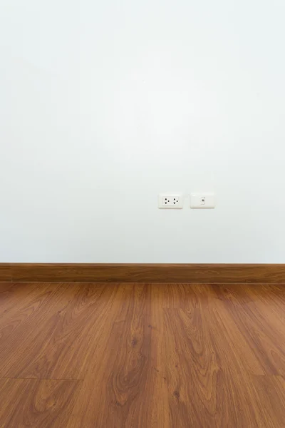 Empty room with brown wood laminate floor and white mortar wall — Stock Photo, Image