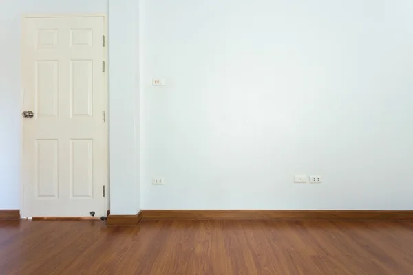 Sala vazia com piso laminado de madeira marrom e parede de argamassa branca — Fotografia de Stock