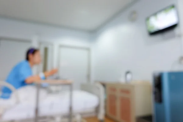 Pacient sedí na posteli, rozmazání obrazu pozadí nemocnice — Stock fotografie