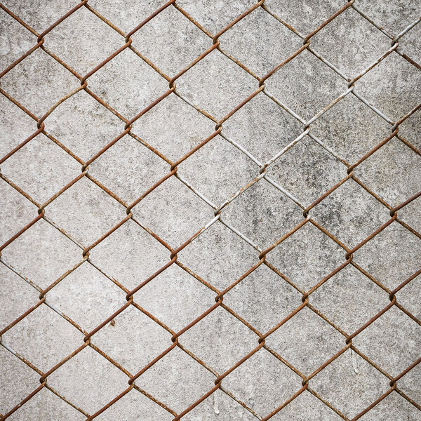 Rusty iron chain wire fence on cement wall background
