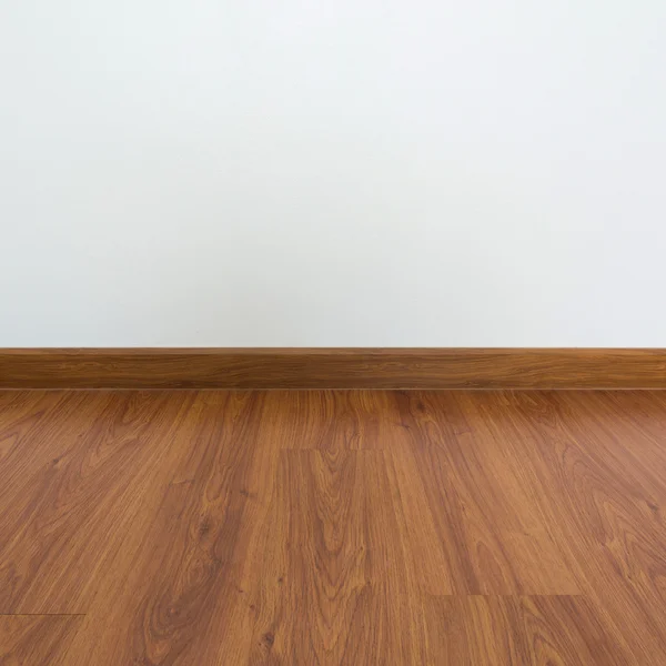 Sala vazia com piso laminado de madeira marrom e parede de argamassa branca — Fotografia de Stock