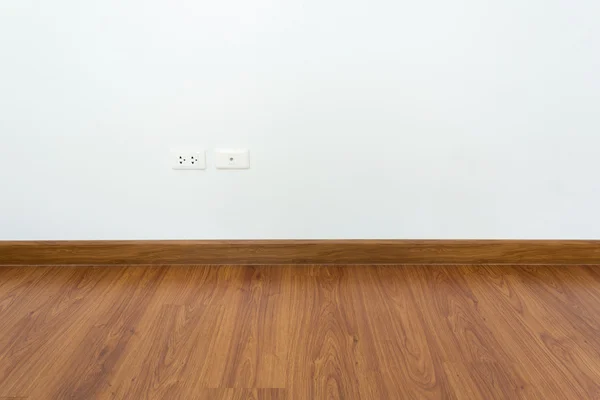 Empty room with brown wood laminate floor and white mortar wall — Stock Photo, Image