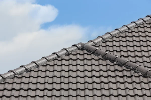 Schwarzes Ziegeldach des Hauses mit blauem Himmel und Wolkenhintergrund — Stockfoto