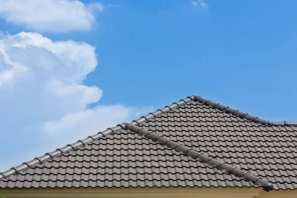 青い空と雲の背景の家の黒瓦の屋根 — ストック写真