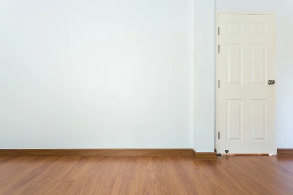 Empty room with brown wood laminate floor and white mortar wall — Stock Photo, Image
