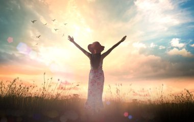 Praise and worship God concept: Silhouette of healthy woman raised hands for praise and worship God at autumn sunset meadow background clipart