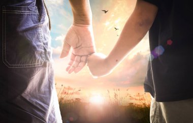 Babalar Günü konsepti: Oğul babasının elini tutuyor sonbahar gündoğumu arka planında çayırda