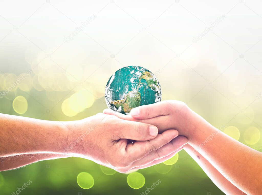 International day of peace concept: Children hands holding earth global over blurred abstract nature background. Elements of this image furnished by NASA
