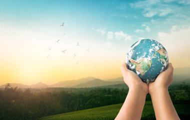 Dünya Çevre Günü konsepti: Dünya 'yı dağ gündoğumu arka planında tutan insan elleri. Bu görüntünün elementleri NASA tarafından desteklenmektedir