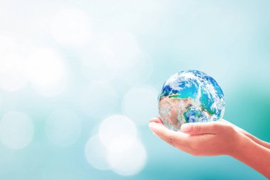 Sustainable development goals (SDGs) concept: Human hands holding earth global over blurred blue water background. Elements of this image furnished by NASA clipart