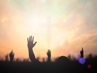 Worship God concept: Silhouette christian people hand rising over blurred cross on spiritual light background clipart