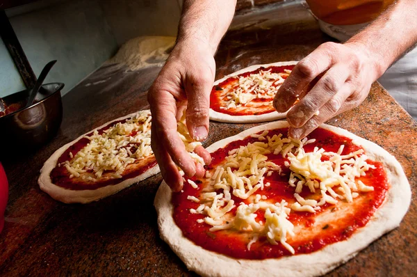 Pizza maken: toevoegen van kaas — Stockfoto