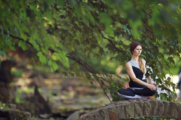 Junge Frau macht Yoga-Übungen in Parkbrücke. — Stockfoto