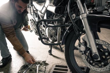 Garajda motosikleti tamir eden deri ceketli genç adam. İnsanın hobi konsepti