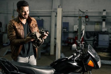 Motosikleti tamir ederken detayları elinde tutan genç bir adam. İnsanın hobi konsepti