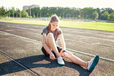 Kız dinleniyor ve koşu yolunda oturuyor.