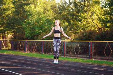 Gülümseyen kız ip atlıyor.