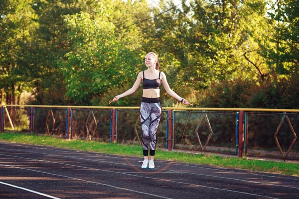 Gülümseyen kız ip atlıyor.