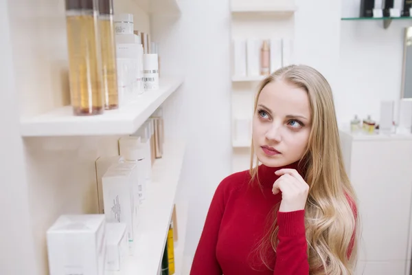 Mujer joven eligiendo productos cosméticos en una farmacia — Foto de Stock