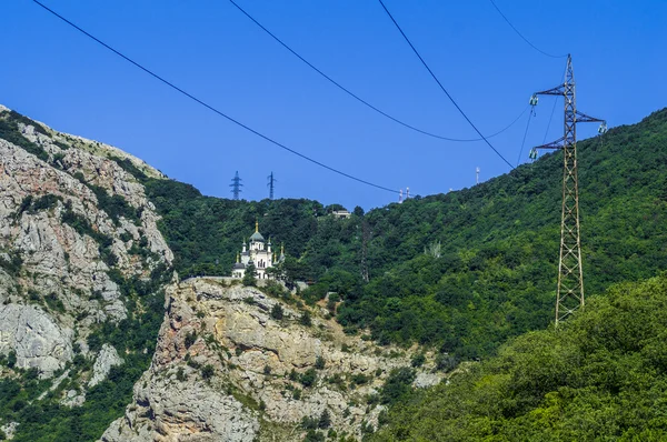 Orthodoxe Kirche in den Bergen und Hochspannungsleitung — Stockfoto