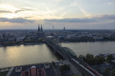 Köln Katedrali ve Hohenzollern Köprüsü 'nün Akşam Panoraması. Köln Katedrali, Ren Nehri, Hohenzollern Köprüsü ve üzerinde seyahat eden trenler.