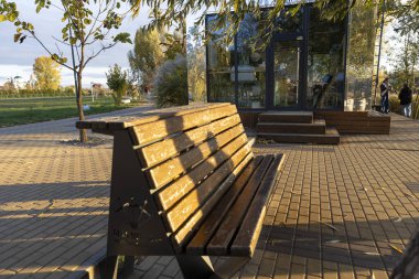 Güneşle aydınlatılmış bir parkta ahşap bir bank.