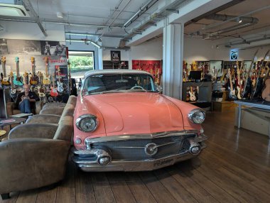 Köln, Almanya - 26 Eylül 2025: Pembe bir vintage araba bir müzik dükkanının içinde duruyor, ilginç ve göz alıcı bir ekran yaratarak retro tarzı yaratıcı, eğlenceli bir atmosferle harmanlıyor..