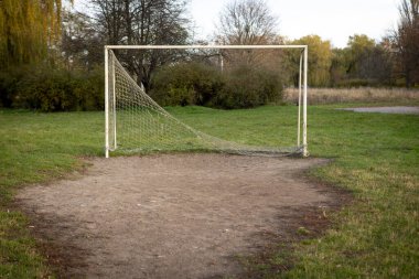 Açık hava spor sahasında bir gol, dayanıklılığı ve yıpranmış bir sahada zamanın geçişini sembolize ediyor..