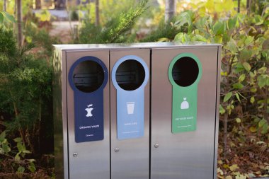 Atık ayıklama, kentsel alanlarda yeşil ve çevre dostu bir konsepti teşvik etmek için tasarlanmış modern parlak metal bir çöp kutusu..