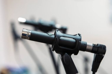 Bir stüdyoda mikrofonlara yakın çekim yapmak, sesi hassasiyetle yakalamak, müzik veya ses kaydetmek için kontrol altında tutulan kablolar ve ekipmanlarla çevrili olmak..