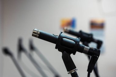 Bir stüdyoda mikrofonlara yakın çekim yapmak, sesi hassasiyetle yakalamak, müzik veya ses kaydetmek için kontrol altında tutulan kablolar ve ekipmanlarla çevrili olmak..