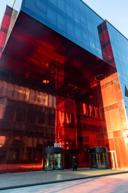 Kyiv, Ukrayna, 3 Kasım 2025: Pırıl pırıl kırmızı cam cepheli modern bir iş merkezi ve iş ufkunu yansıtan çağdaş bir mimari.