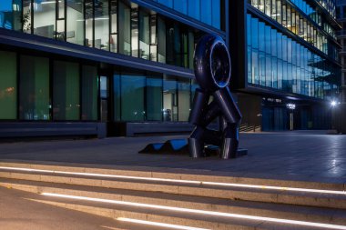 Kyiv, Ukrayna, 3 Kasım 2025: Çağdaş sanatla şık şehir mimarisini harmanlayan, modern bir iş merkezinin ortasında oturan bir adamın heykeli duruyor.