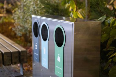 Atık ayıklama, kentsel alanlarda yeşil ve çevre dostu bir konsepti teşvik etmek için tasarlanmış modern parlak metal bir çöp kutusu..