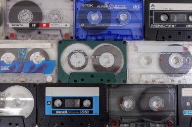 Çeşitli eski ses kasetleri sade bir arka planda, gösterişli retro tasarım, renkli etiketler ve müzik tarihinin nostaljik unsurları üzerine düzenlenmiştir..