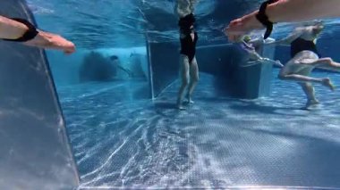 Bir adam berrak bir havuzda zarif bir şekilde yüzer. Suyun içinden süzülen ışıkla birlikte sakin ve akışkan bir sahne yaratır..